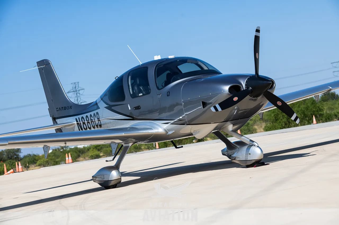 A silver and grey Cirrus SR22 aircraft with registration N886CB parked on an airfield.
