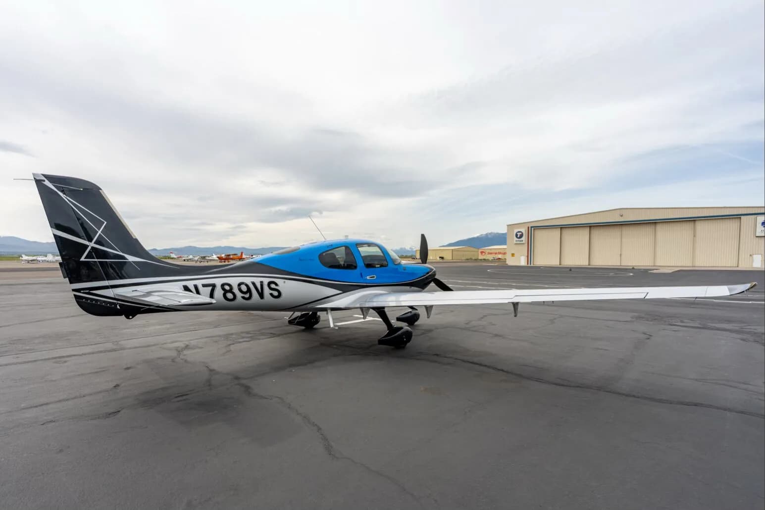Three-quarter rear view of a black, blue, and silver single-engine aircraft with registration N789VS parked on an airfield.