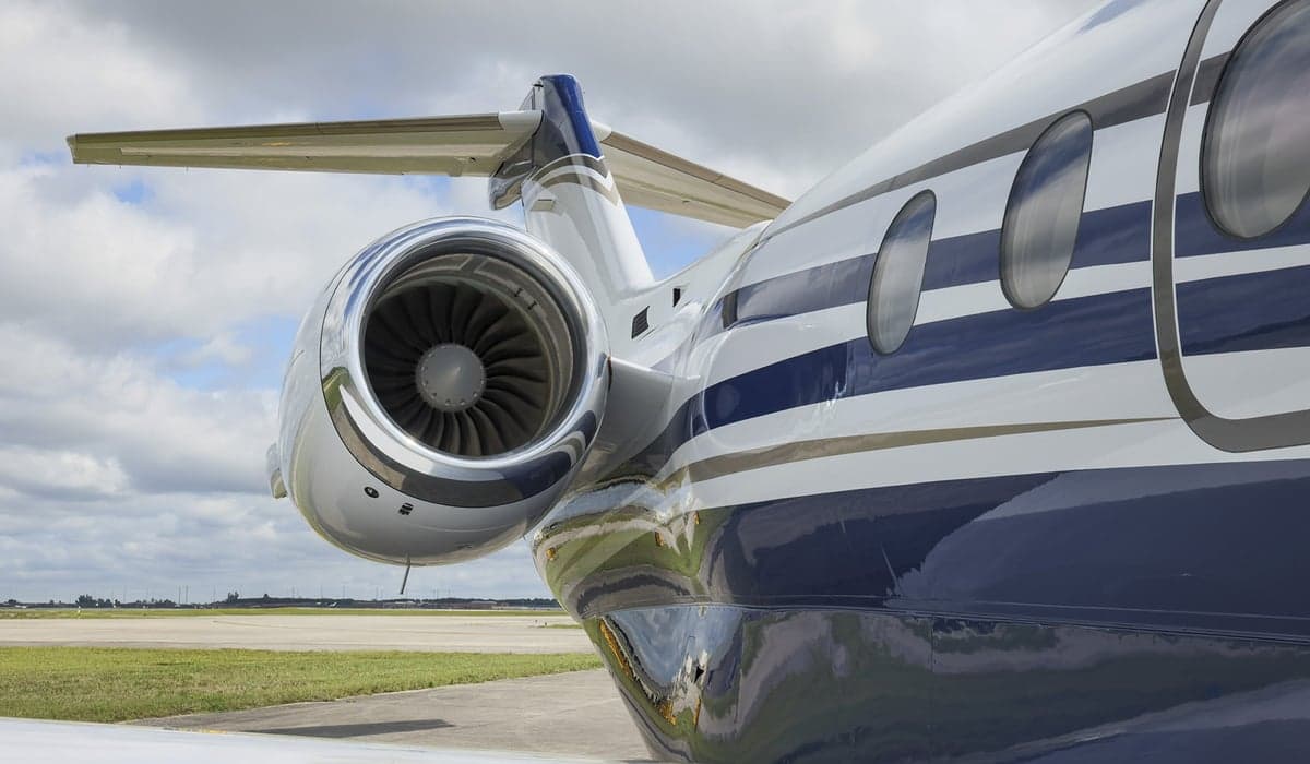 Close-up of the tail and engine of a white and blue jet aircraft.