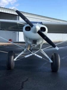 Front view of a white and red Piper Cub with tundra tires.