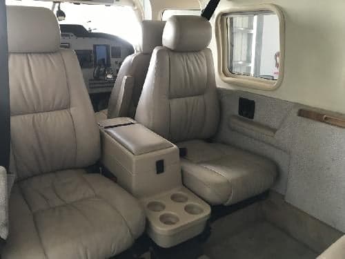 The interior of the aircraft features light-colored leather seats and a center console with cup holders.