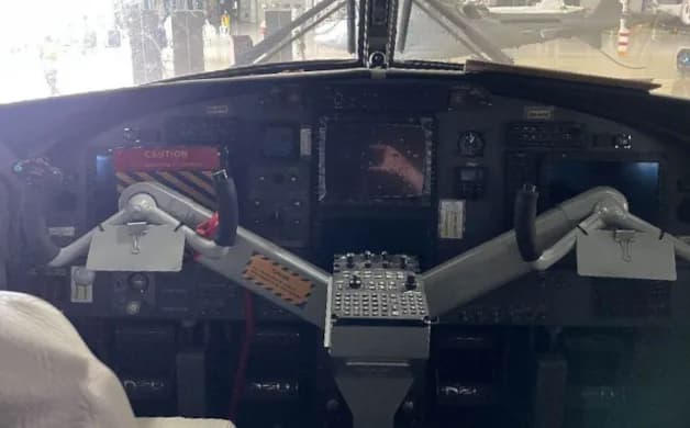 The cockpit instrument panel of an aircraft with dual yokes and various displays.