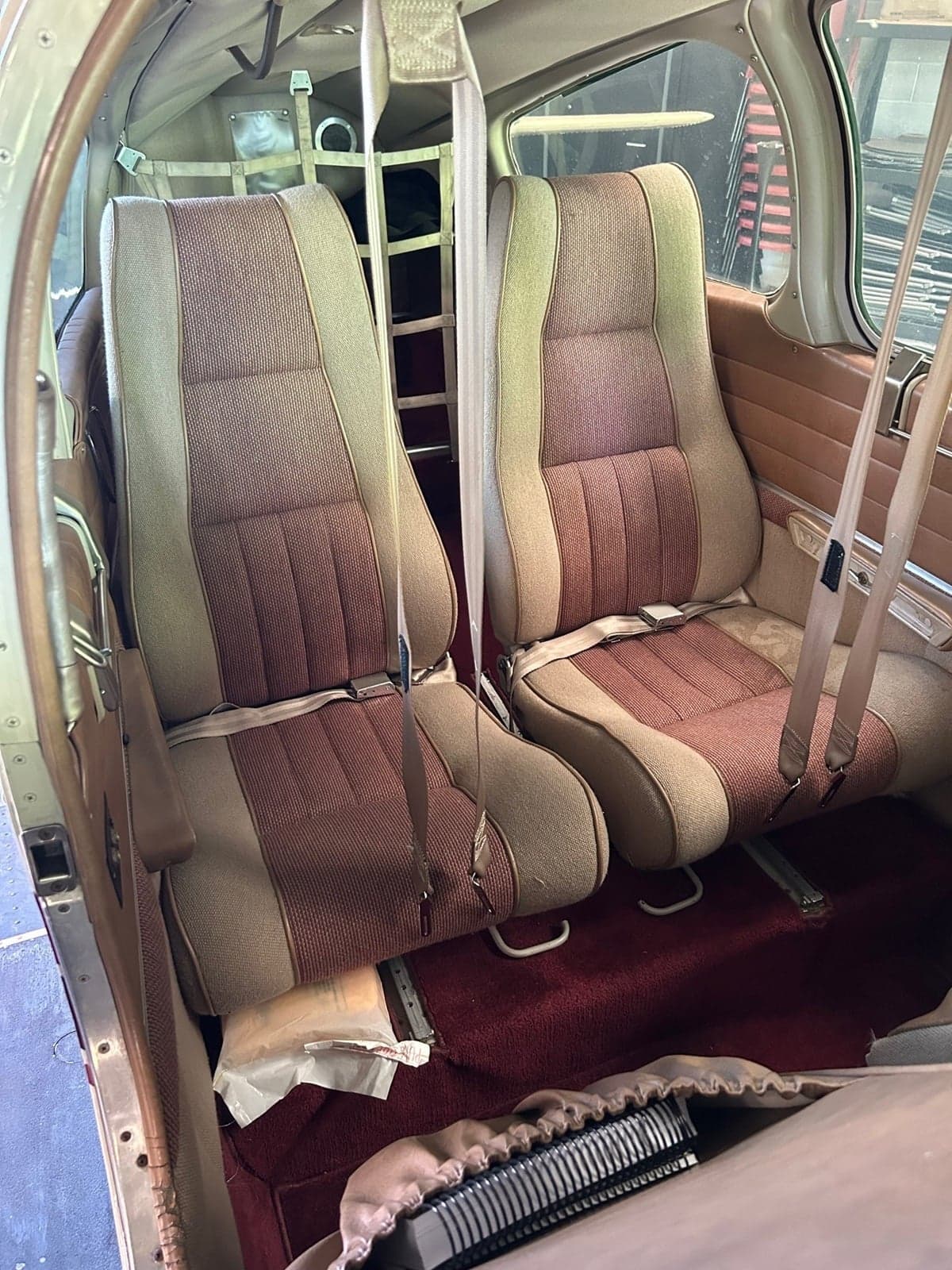 The rear passenger seats of an aircraft with beige and brown fabric upholstery.
