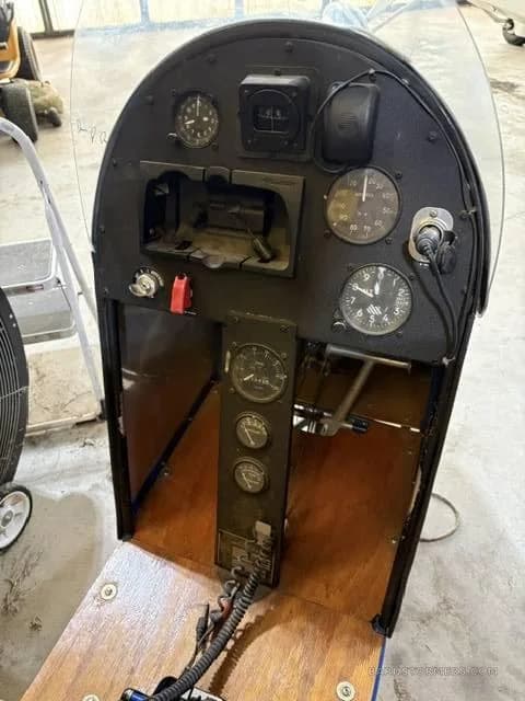 The black instrument panel of an ultralight aircraft with various gauges and controls.