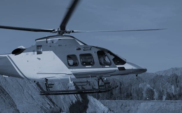 A helicopter flies over a mountainous landscape.