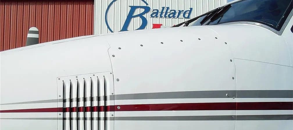 Close-up of the nose of a Beechcraft King Air B200 with the Ballard Aviation logo in the background.