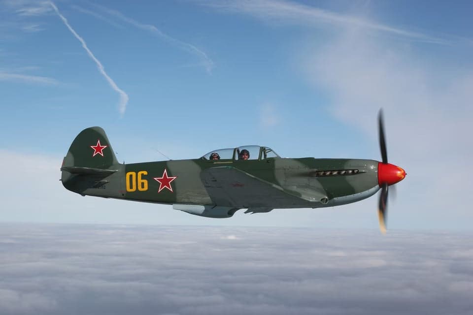 Yak-3 flying head-on over a city.