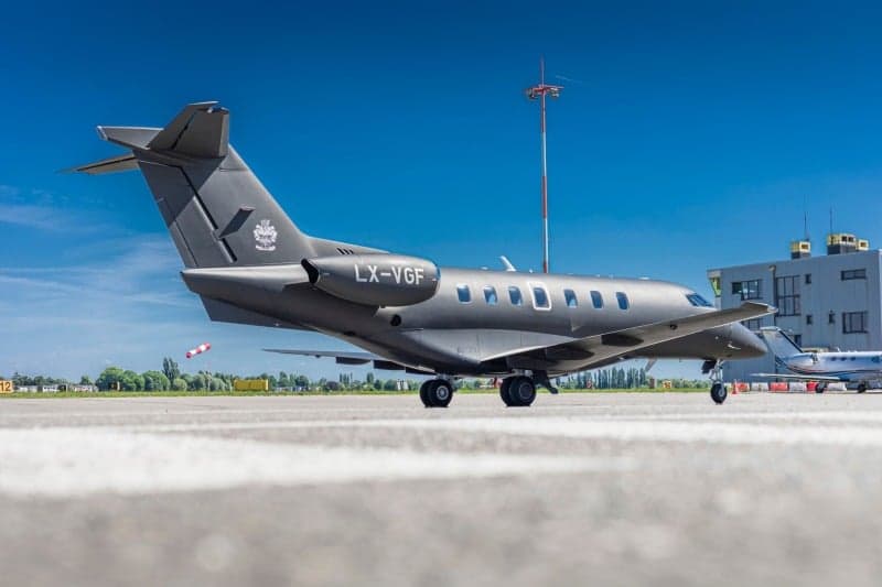 A Bombardier Challenger 350 aircraft with registration LX-VGF is parked on the tarmac at an airport.