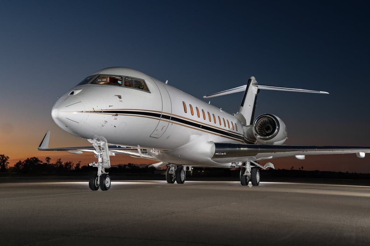 A Bombardier Global Express aircraft parked on the tarmac at dusk.