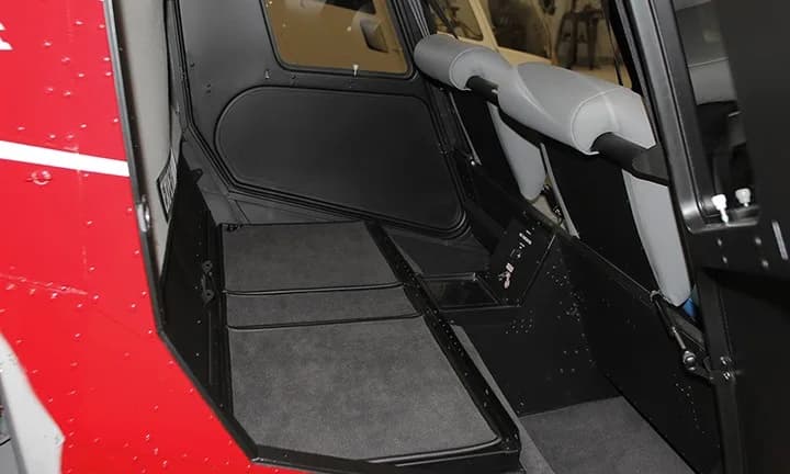 The interior of a Robinson R44 helicopter, showing the seats and flooring.