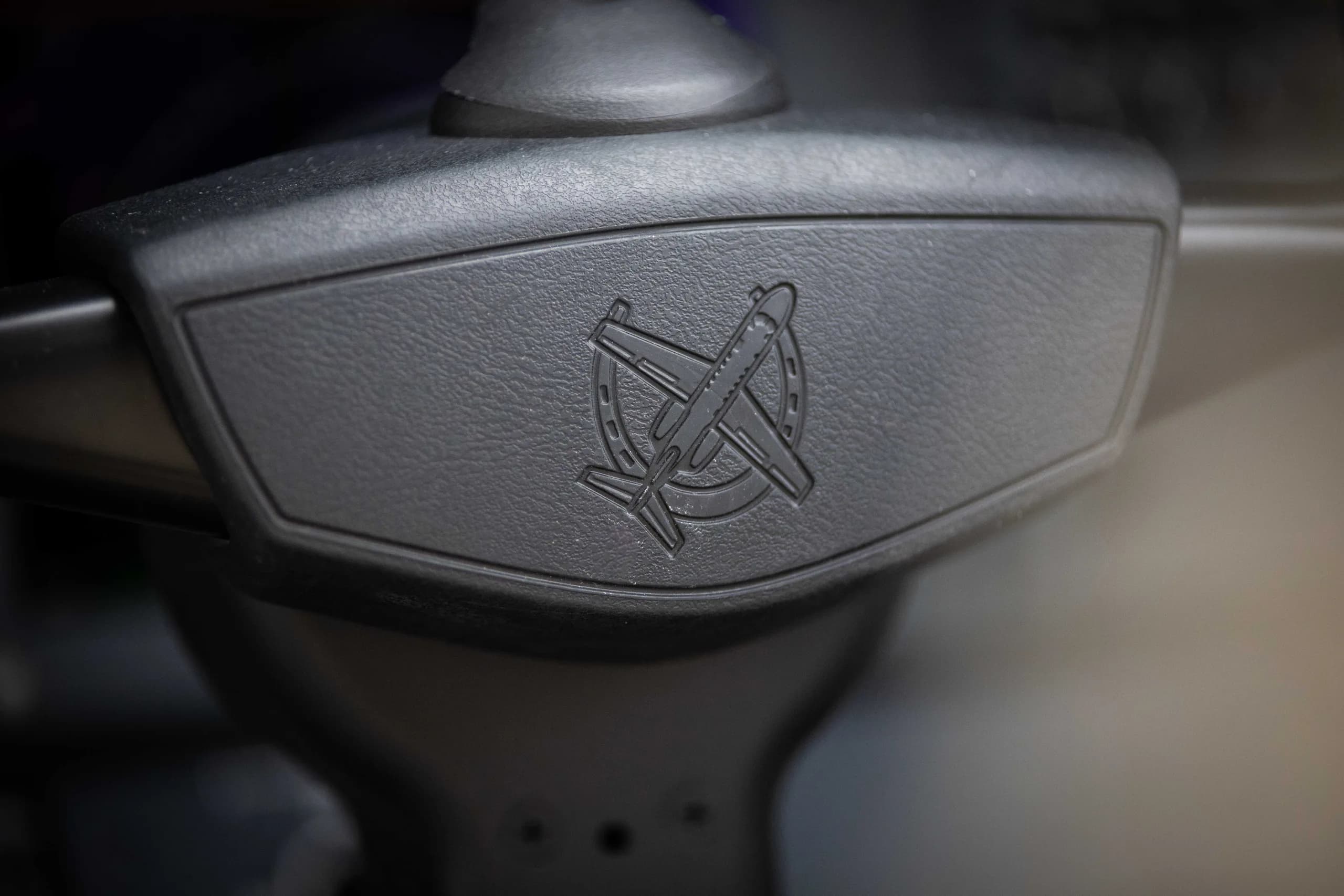 A close-up of an embossed aircraft logo on a control yoke.