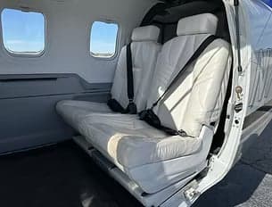Rear cabin seats of the aircraft with white leather upholstery.