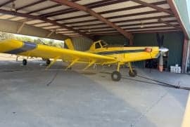 A yellow Air Tractor aircraft parked inside a hangar.