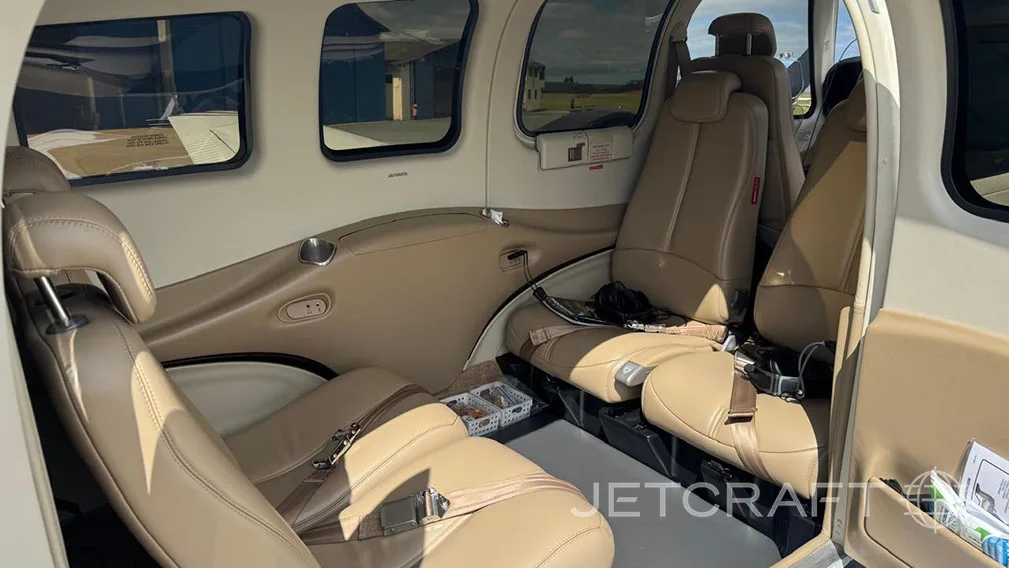The aircraft's interior features tan leather seats and side storage compartments.