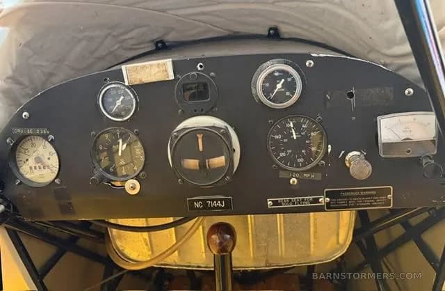 A close-up of the vintage instrument panel of a small aircraft, showing various gauges and controls.