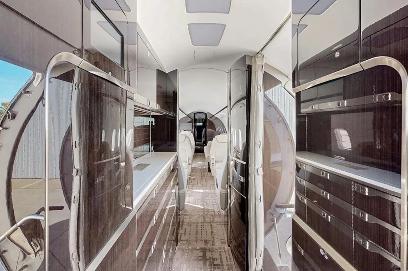 The aircraft's galley area with dark wood cabinetry and a view towards the main cabin.