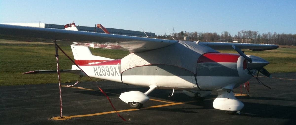 Cessna 177 Cardinal with a red and gray paint scheme parked on the tarmac with a cover.