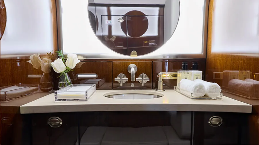 The elegant lavatory vanity of a private jet with a sink, mirror, and toiletries.