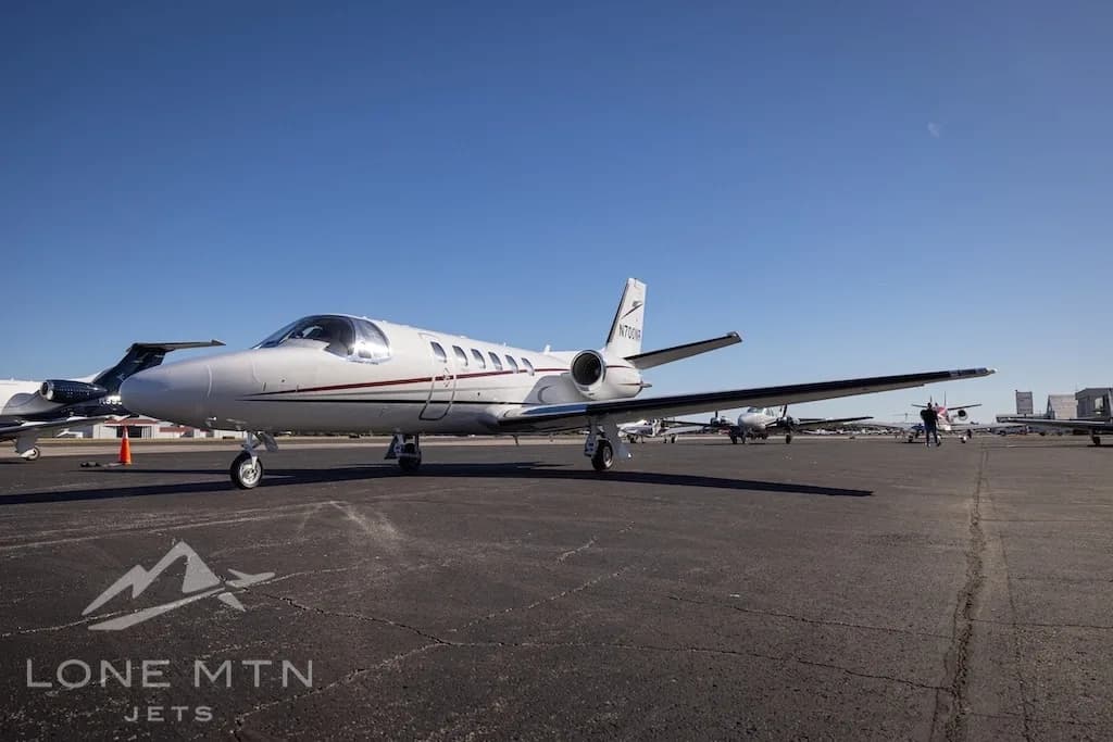 A white Cessna Citation Bravo business jet, tail number N700NR, parked on an airport tarmac under a clear blue sky.