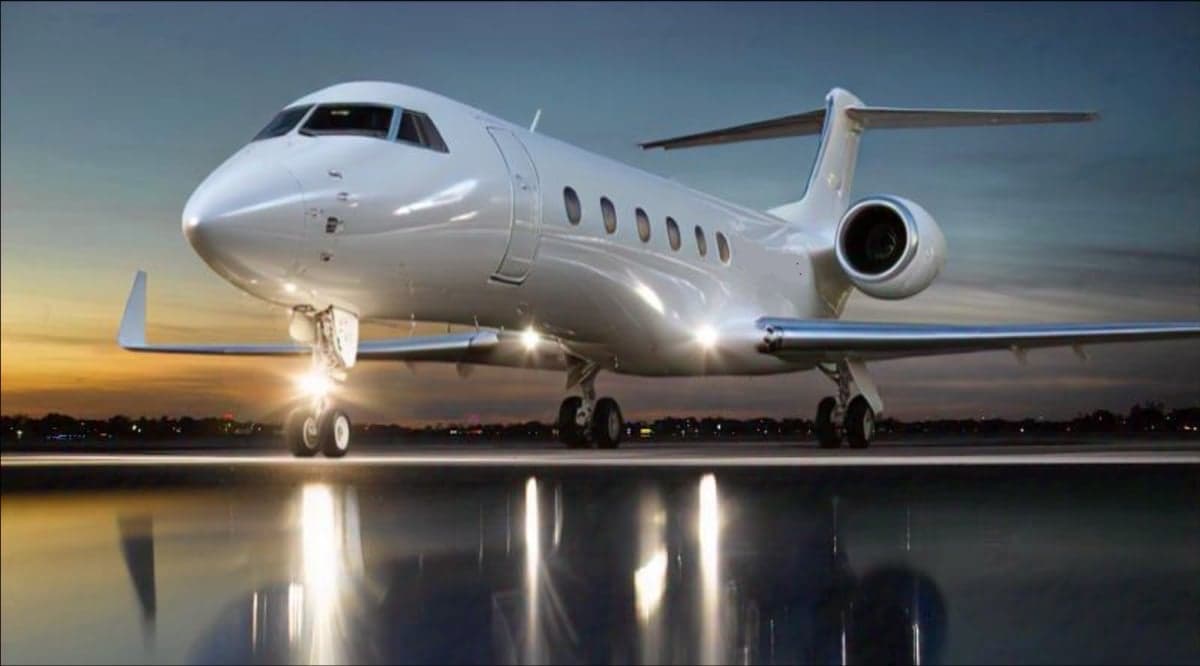 A white jet aircraft parked on the tarmac at sunset.