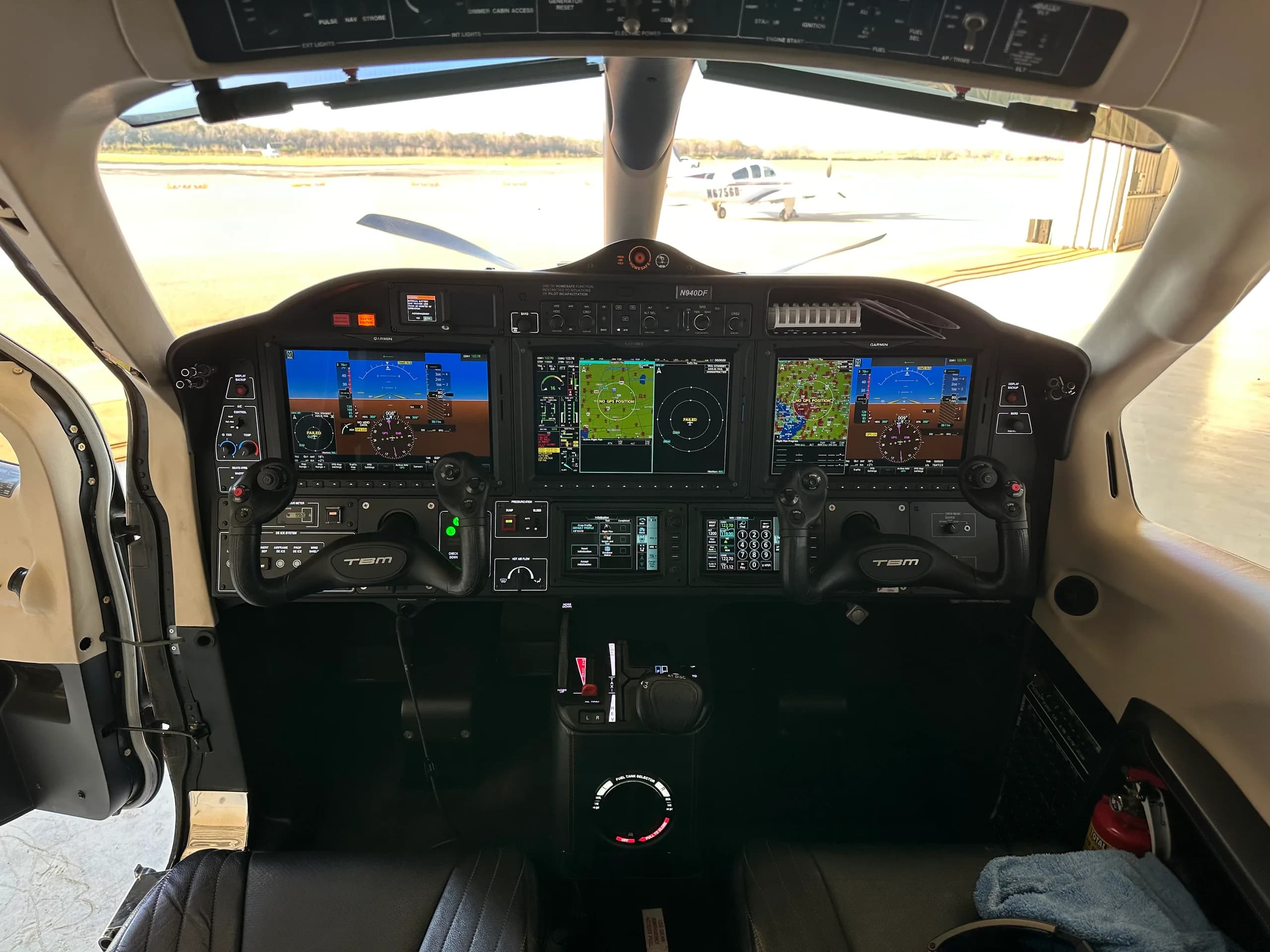 The cockpit of a TBM 940 aircraft with multiple digital displays and controls.