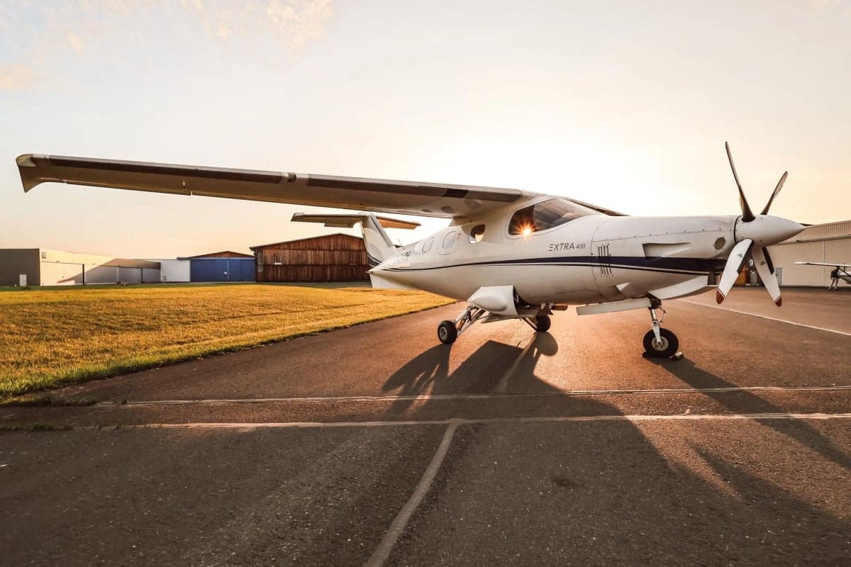 Extra 400 aircraft D-ETTH parked on the tarmac with the sun setting in the background.