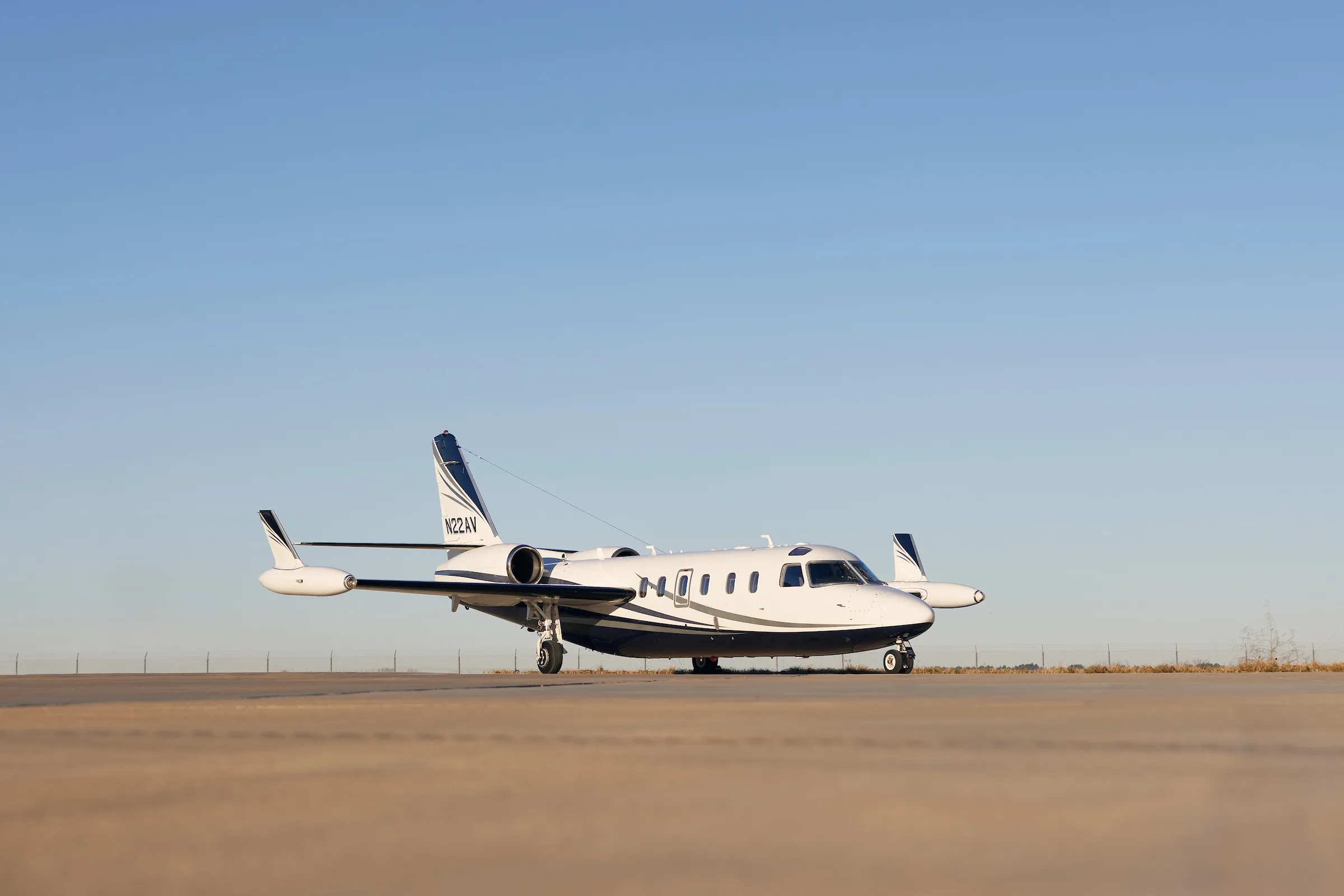 A white and blue jet aircraft sits on the tarmac under a clear blue sky.