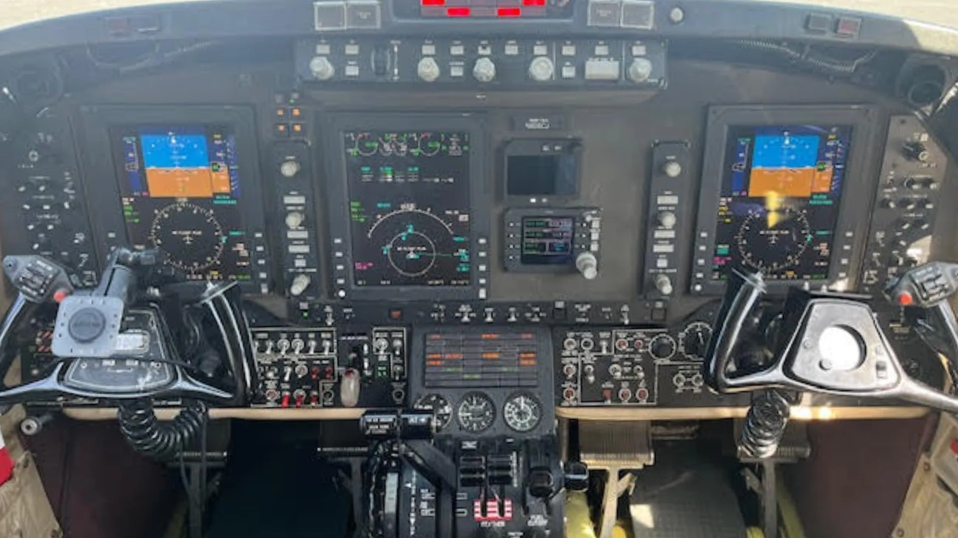 The cockpit of a Beechcraft King Air, showing the instrument panel with multiple digital displays and control yokes.