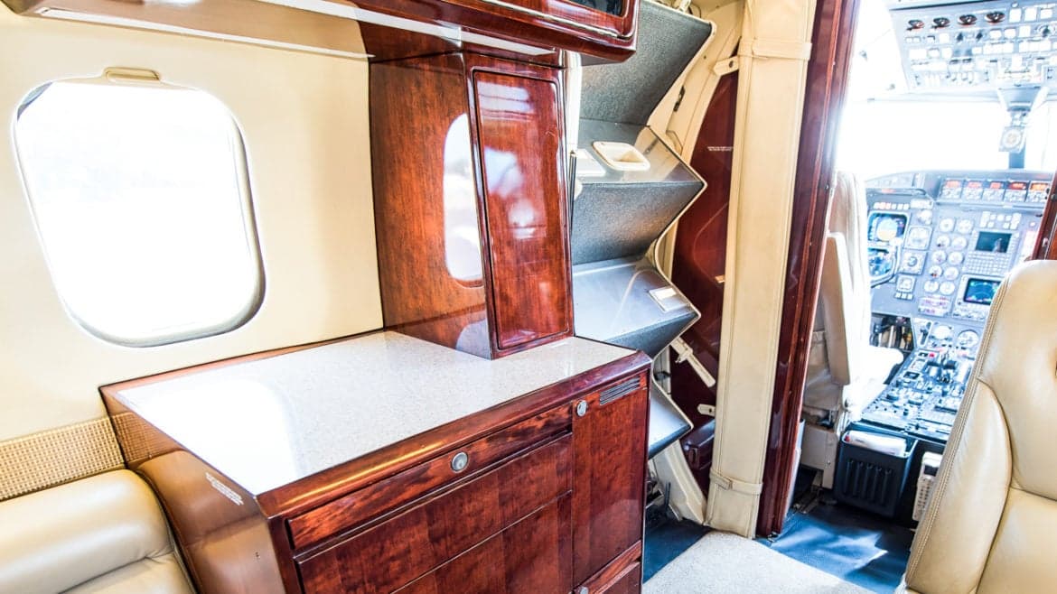 Interior of the aircraft showing a cabinet, seats, and cockpit view.