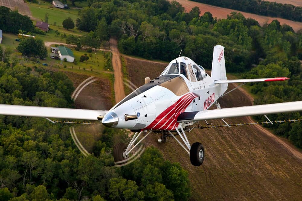 Front view of a Thrush 510G crop duster flying over a rural area.