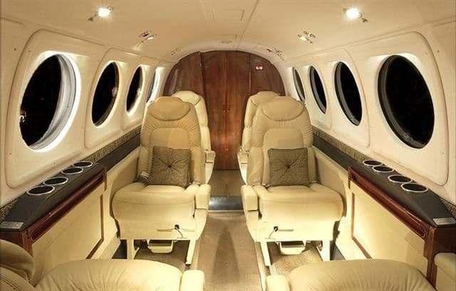 King Air cabin with beige leather seats and oval windows.