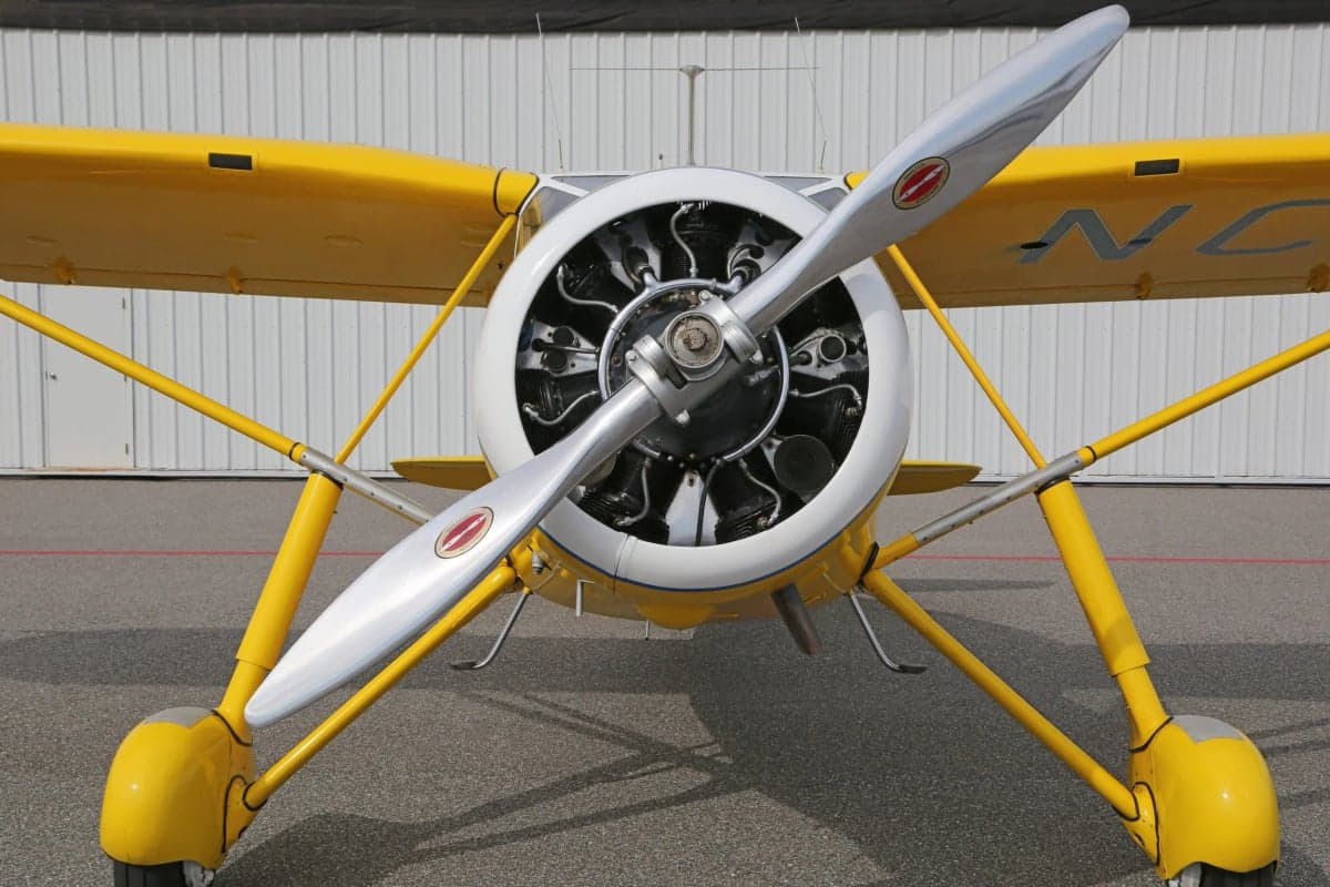 Close up front view of a yellow and white Stinson Reliant's engine and propeller.