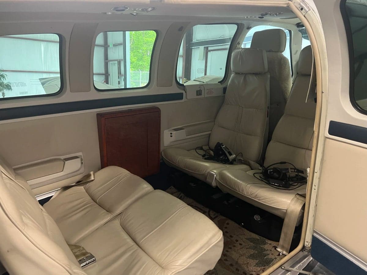The interior of the aircraft features light-colored leather seats and a small table.