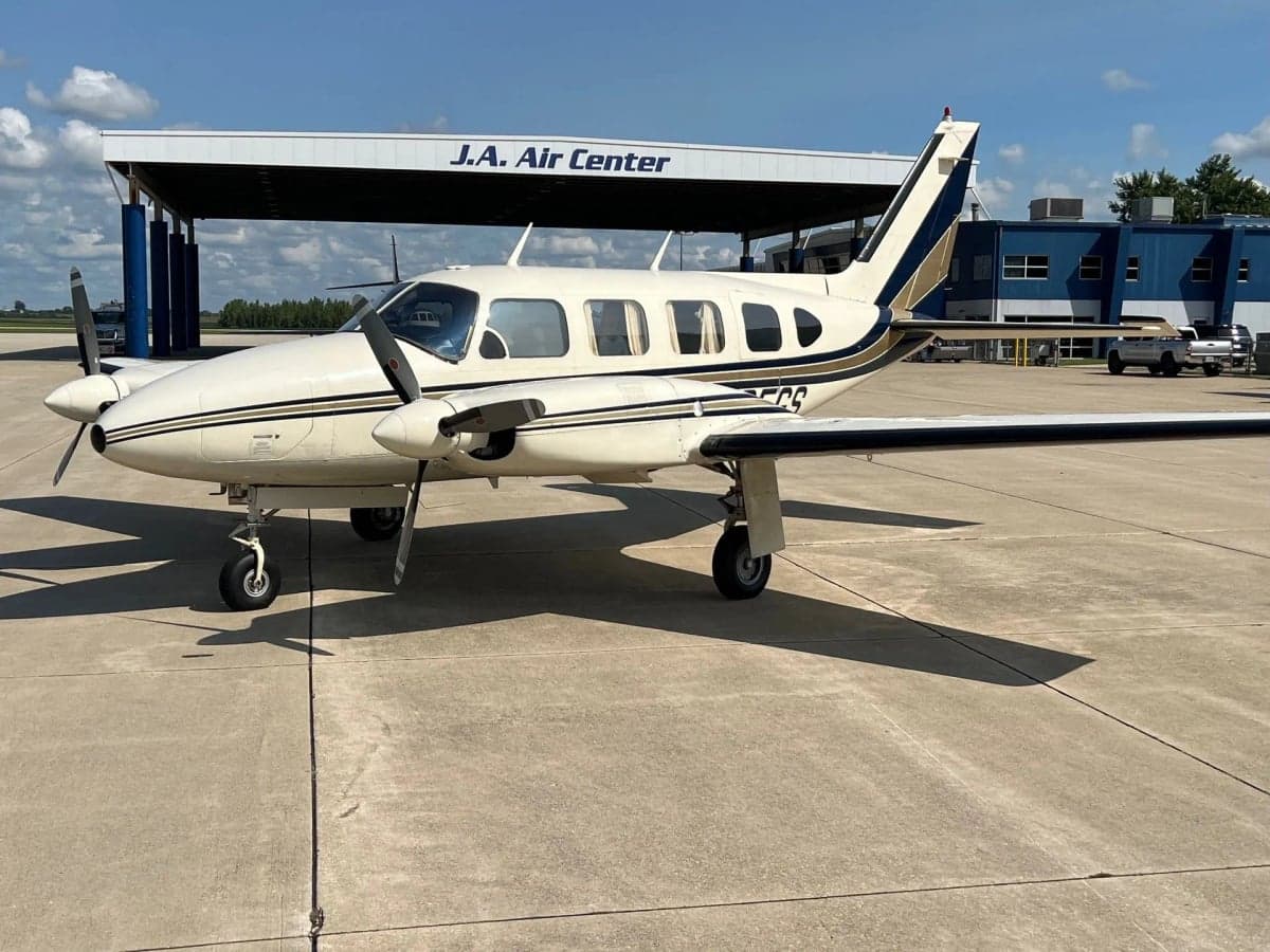 Front view of a light aircraft with a white and maroon paint scheme against a black background.