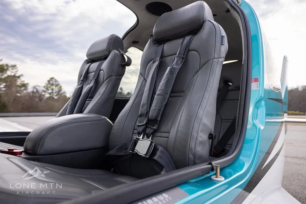 The gray leather front seats of the Cirrus SR22 aircraft cabin, viewed from the side with the door open.