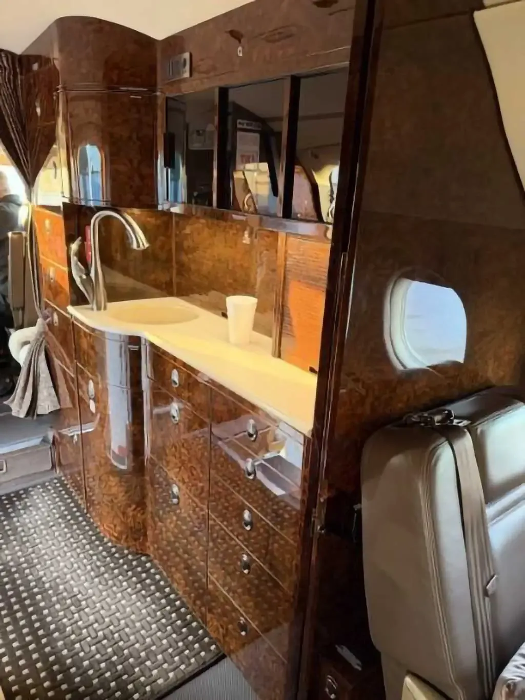 The aircraft's galley area with a sink, faucet, and polished wood cabinetry.
