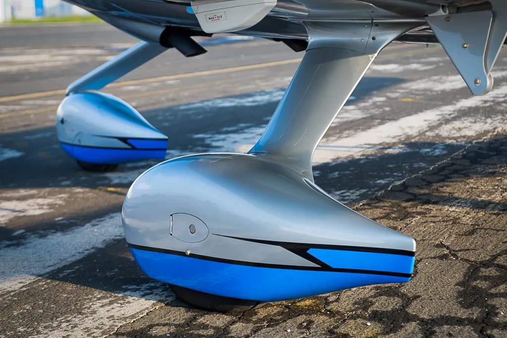 A close-up view of the blue and silver main landing gear fairings of the Cirrus SR22T GTS Carbon aircraft.