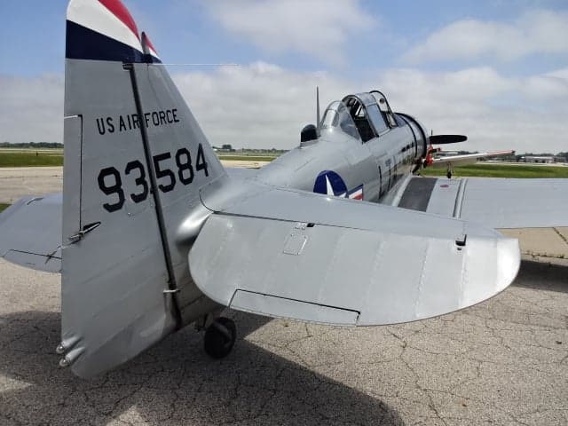 Rear quarter view of the silver T-6 Texan aircraft on the tarmac.