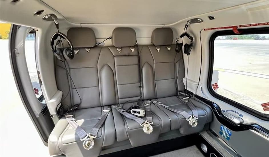 The interior of a helicopter with gray leather seats and headsets.