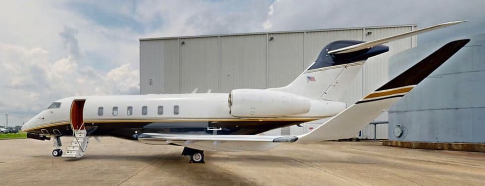 A Challenger aircraft is parked on the tarmac with the entry stairs down.