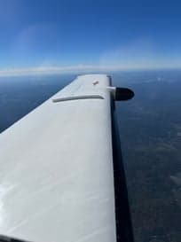 Close up of the front of a white and blue aircraft with a three-blade propeller.