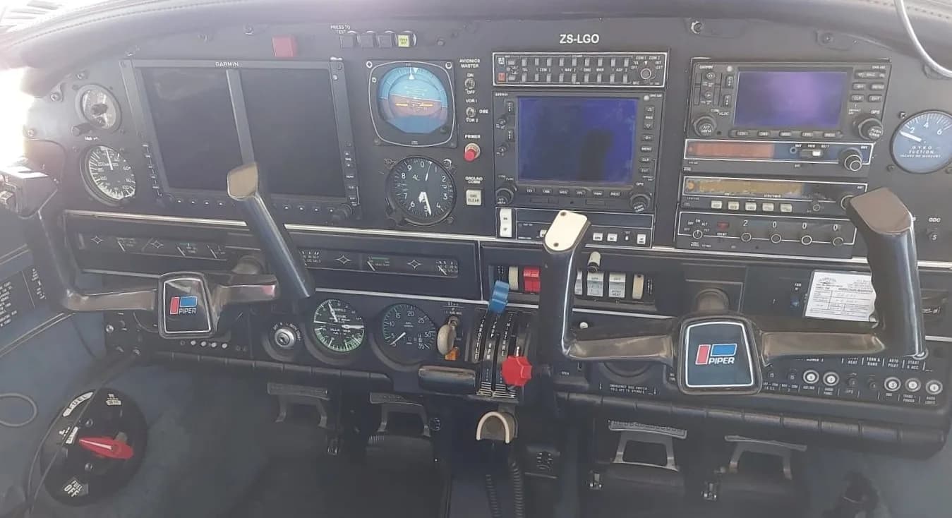The cockpit instrument panel of a Piper aircraft, showing various gauges, screens, and controls.