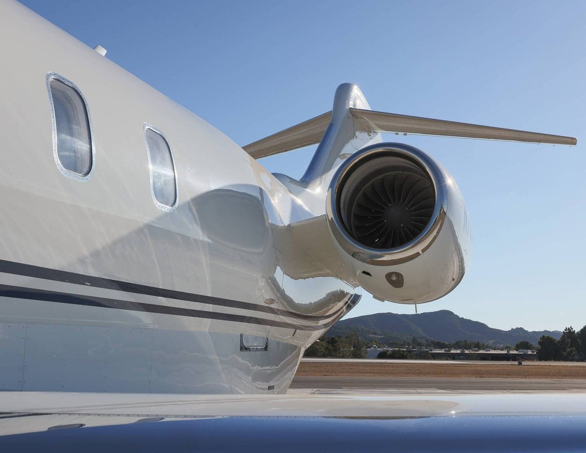 Close up of the tail and engine of a white aircraft on the tarmac.