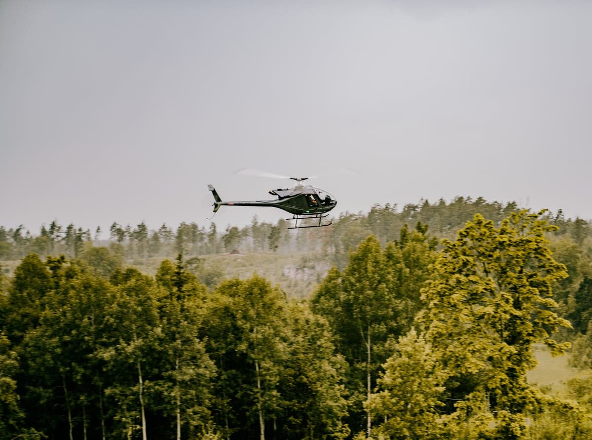 Helicopter flying over a forest landscape.