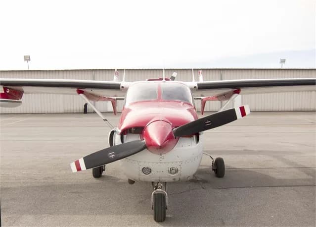 Front view of a red and white Cessna Skymaster on the tarmac.