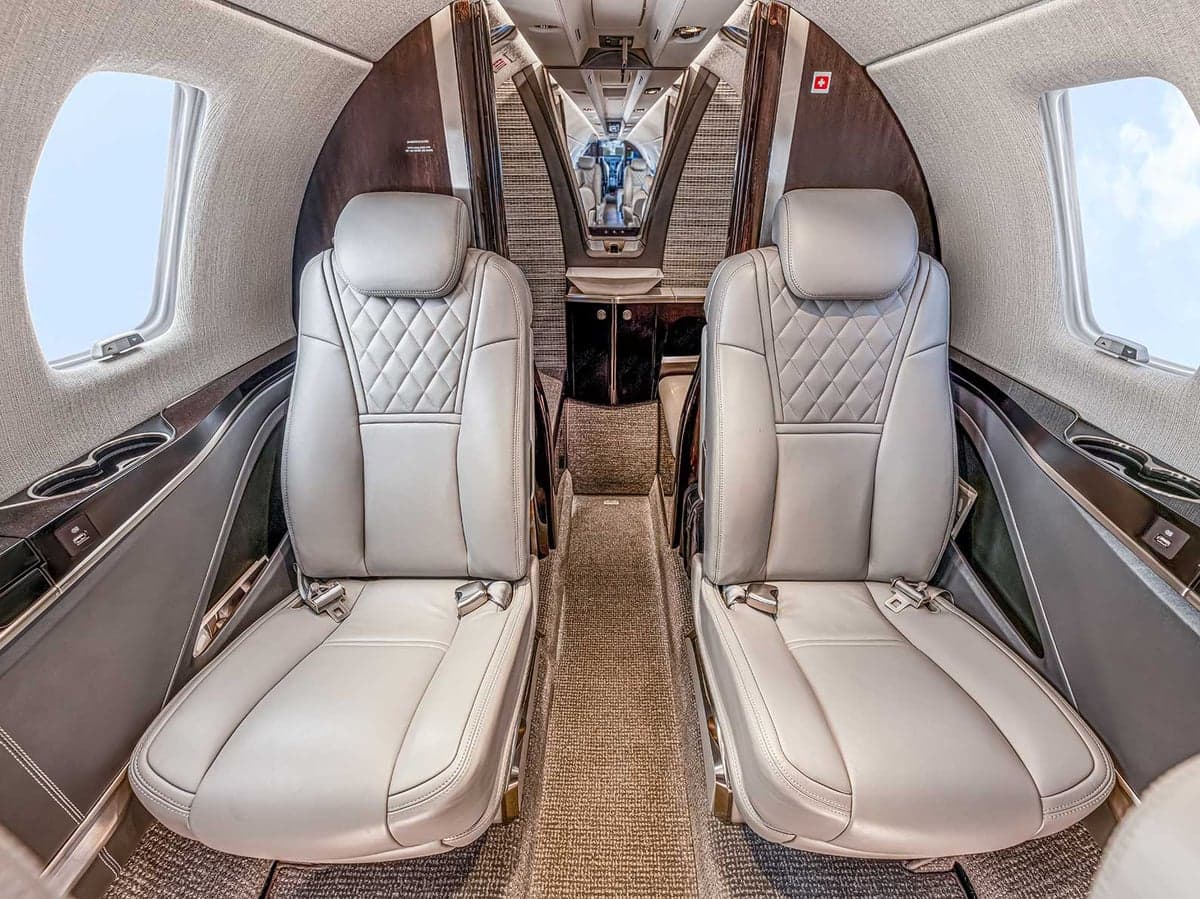 View of the Citation CJ4 cabin featuring gray leather seats and wood trim.