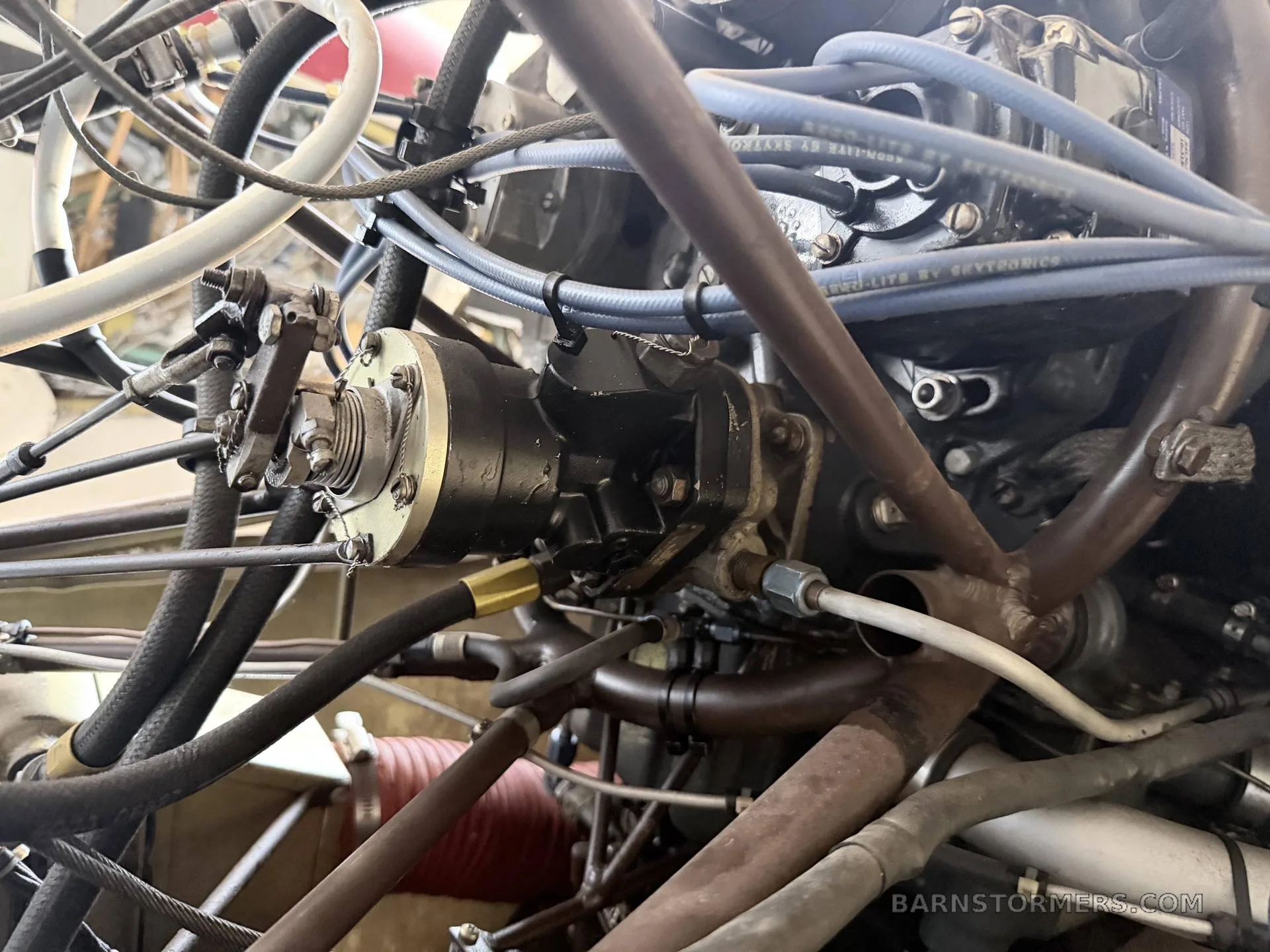 A detailed close-up of various hoses, wires, and mechanical components within an aircraft engine bay.