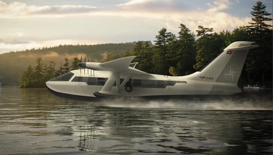 A white Jekta seaplane with twin engines on top of its wing, on a lake at sunset, with trees in the background.