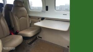 The interior of a Piper PA46-350P Mirage, registration SP-NAZ, showing the seating and a table.