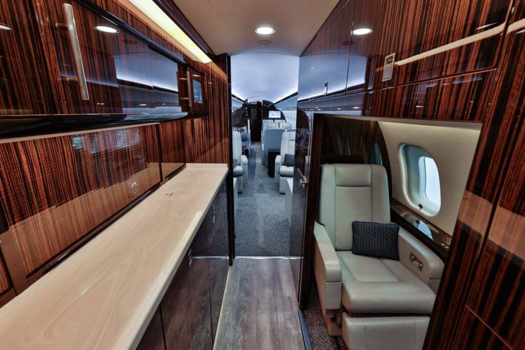 View of the aircraft interior showing a seat, wood paneling, and a countertop.